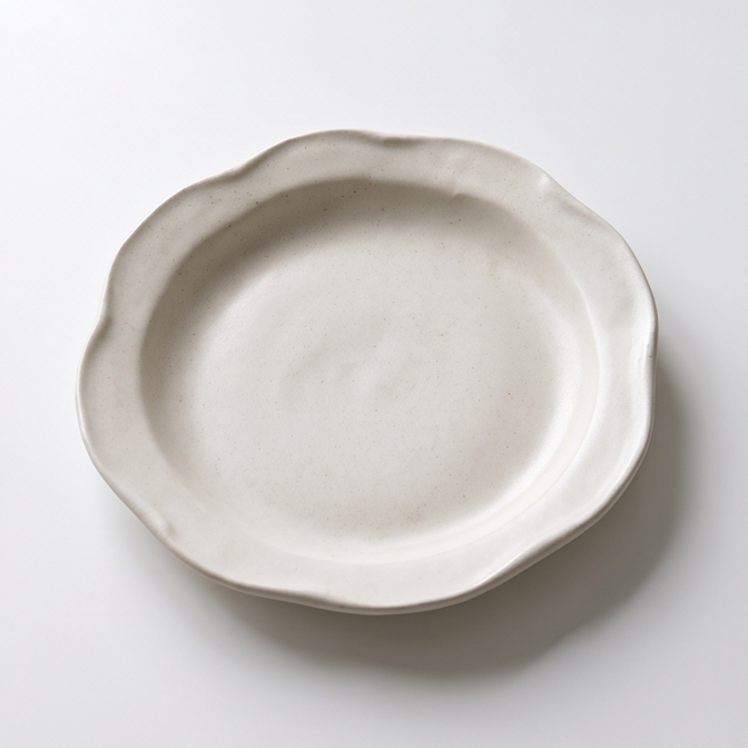 Close-up of handcrafted ceramic dinner plate showing its irregular rim and light speckling